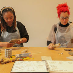 Two workshop participants are seated next to each other, working with clay.