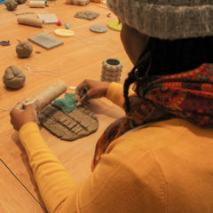 Looking over the shoulder of a workshop participant as they work with clay